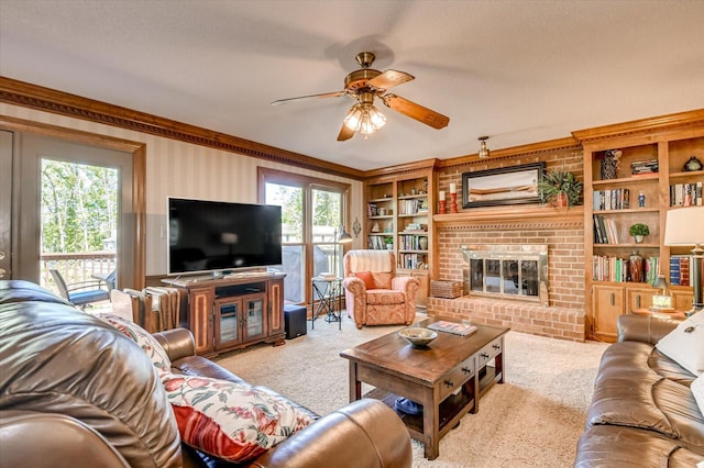 carpeted living area with a brick fireplace, a ceiling fan, built in shelves, and ornamental molding