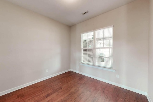 unfurnished room with visible vents, baseboards, and wood finished floors
