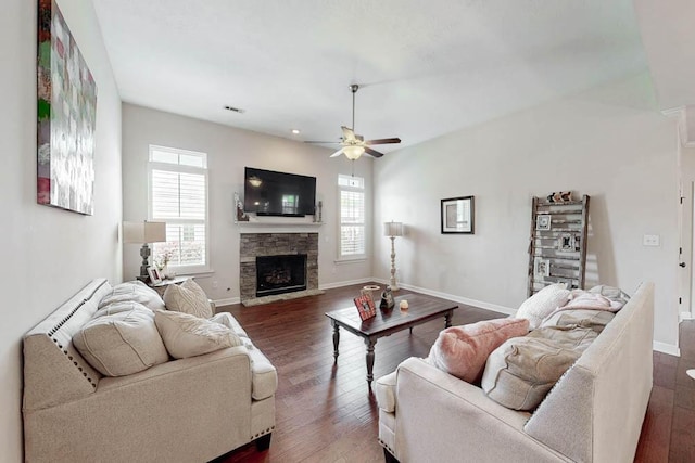 living area featuring baseboards, a ceiling fan, a healthy amount of sunlight, and a fireplace