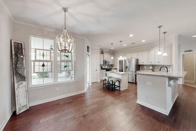 kitchen with dark wood-style flooring, a kitchen bar, white cabinets, an inviting chandelier, and stainless steel appliances