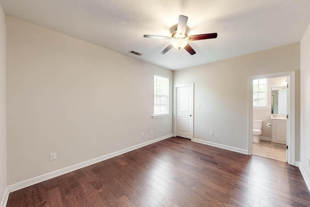 unfurnished bedroom featuring visible vents, multiple windows, and dark wood finished floors
