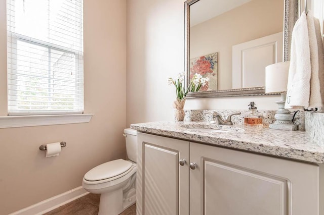 bathroom with baseboards, vanity, and toilet