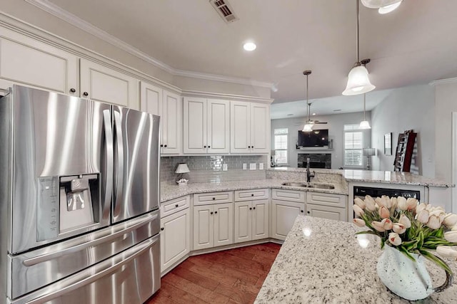 kitchen featuring stainless steel refrigerator with ice dispenser, visible vents, crown molding, dark wood finished floors, and a sink