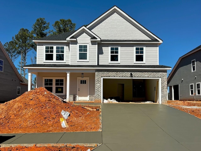 traditional-style home with a porch, concrete driveway, brick siding, and a garage