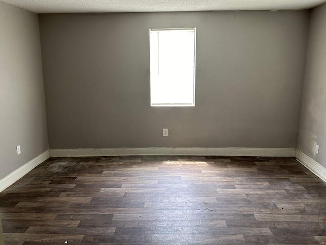 empty room featuring a textured ceiling, dark hardwood / wood-style flooring, and plenty of natural light