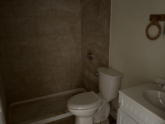 bathroom featuring tile patterned flooring, vanity, toilet, and a tile shower