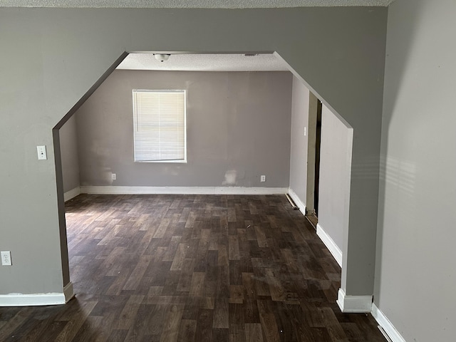 bonus room featuring a textured ceiling and dark wood-type flooring