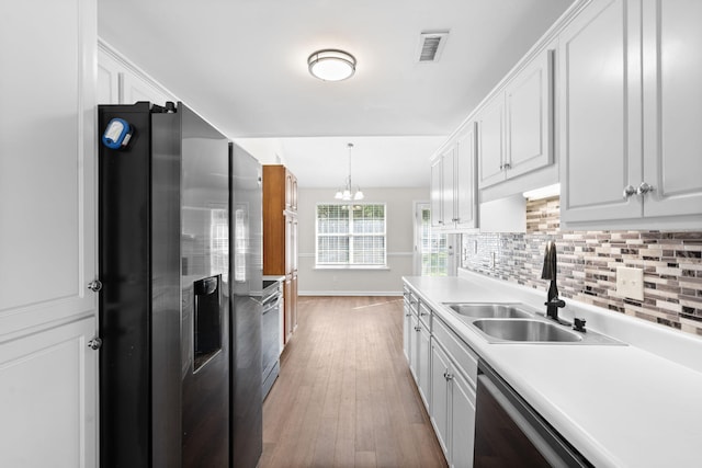 kitchen with tasteful backsplash, hanging light fixtures, white cabinets, sink, and stainless steel appliances