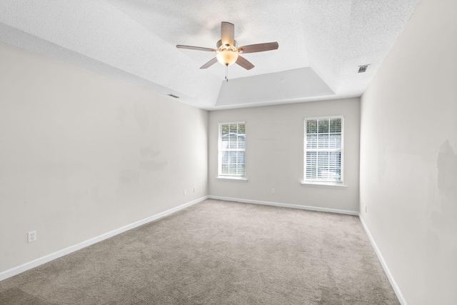 carpeted spare room with ceiling fan, a textured ceiling, and a raised ceiling