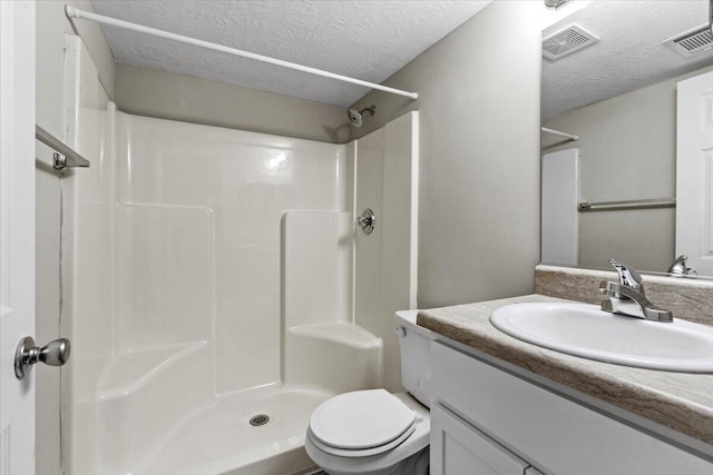 bathroom featuring toilet, vanity, a textured ceiling, and walk in shower