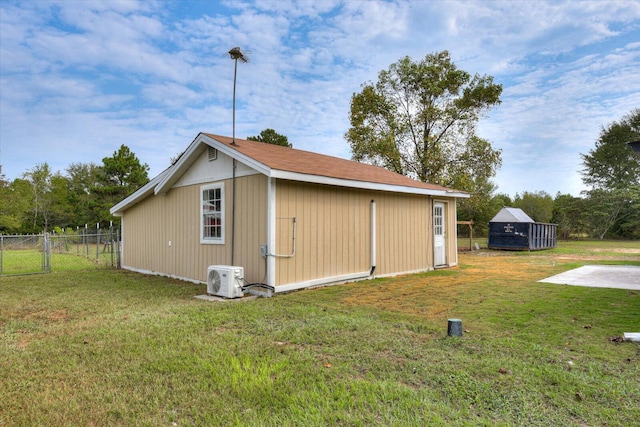 view of outbuilding with ac unit and a yard