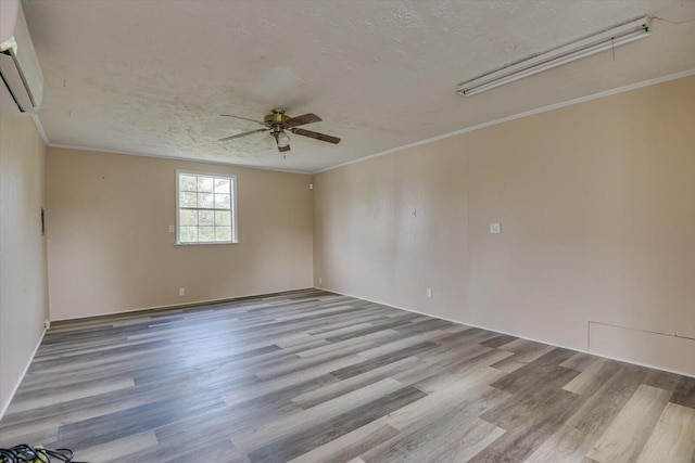 spare room featuring a wall unit AC, ceiling fan, light hardwood / wood-style floors, and ornamental molding