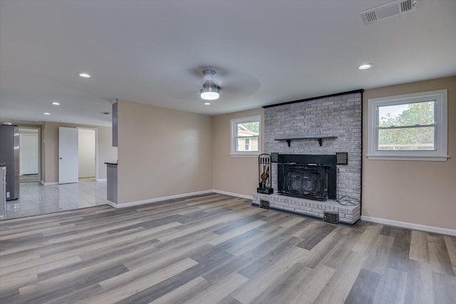 unfurnished living room with ceiling fan, light hardwood / wood-style flooring, and a brick fireplace