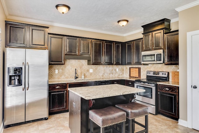 5558 Connor Dr, Evans, GA 30809 - kitchen with appliances with stainless steel finishes, a center island, dark brown cabinets, decorative backsplash, and crown molding
