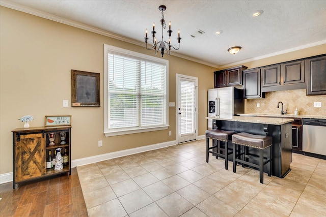 5558 Connor Dr, Evans, GA 30809 - kitchen featuring appliances with stainless steel finishes, a chandelier, crown molding, a kitchen bar, and a kitchen island