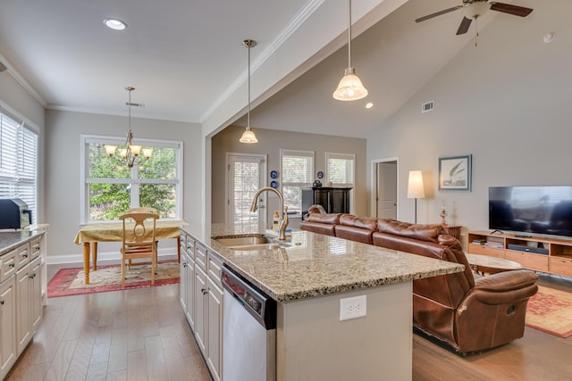 kitchen with open floor plan, a kitchen island with sink, dishwasher, and hanging light fixtures