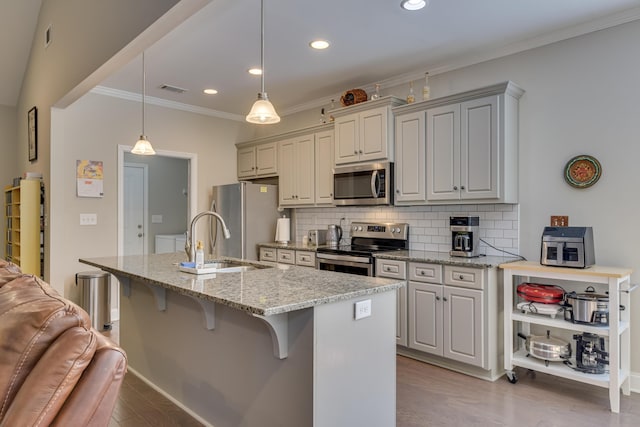 kitchen featuring stainless steel appliances, light stone counters, backsplash, and decorative light fixtures