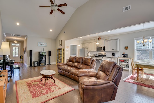 living area with high vaulted ceiling, wood-type flooring, visible vents, and crown molding