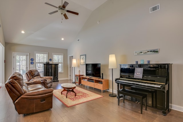 living area with visible vents, a ceiling fan, wood finished floors, high vaulted ceiling, and baseboards