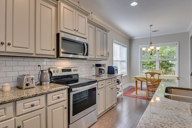 kitchen featuring stainless steel appliances, crown molding, hanging light fixtures, and tasteful backsplash