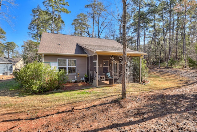 view of front of house with a shingled roof, a sunroom, and a front lawn