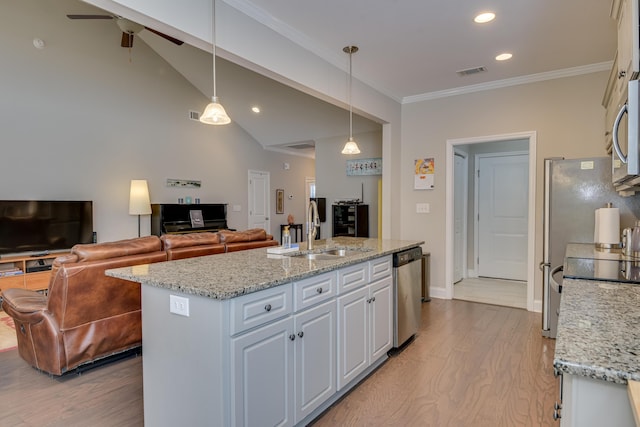 kitchen featuring an island with sink, appliances with stainless steel finishes, open floor plan, pendant lighting, and a sink