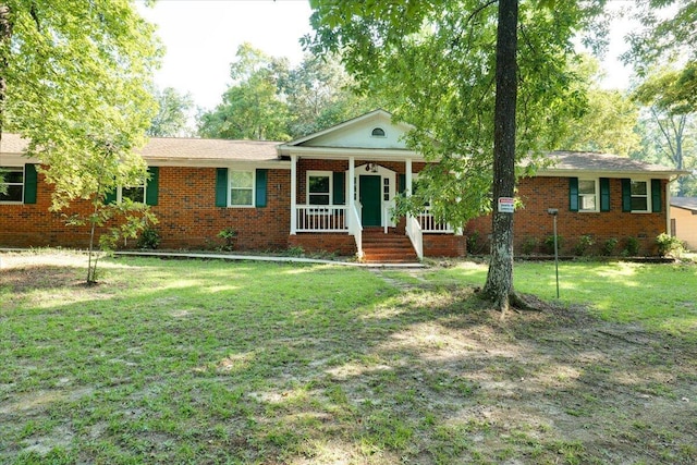 ranch-style home featuring covered porch and a front yard