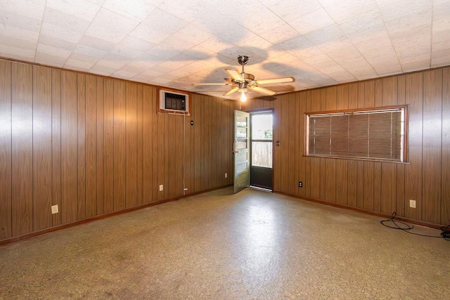 spare room featuring a wall mounted air conditioner, baseboards, ceiling fan, and wood walls