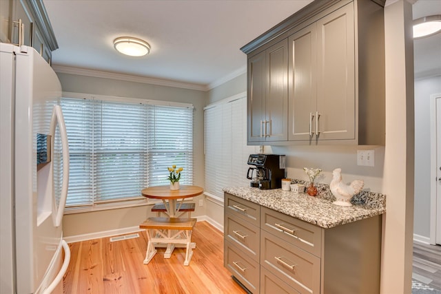 315 Coastal Cv, Mccormick, SC 29835 - kitchen with white fridge with ice dispenser, light wood-type flooring, ornamental molding, baseboards, and light stone counters