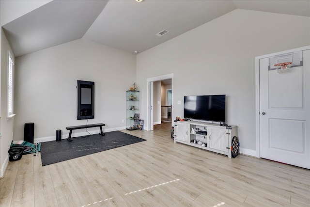 workout room with vaulted ceiling and light wood-type flooring