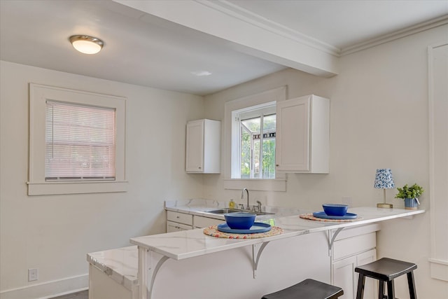 1847 Warren St, Augusta, GA 30904 - kitchen with a sink, a peninsula, baseboards, white cabinetry, and a kitchen bar