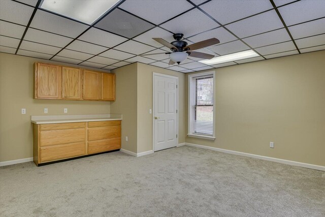 unfurnished bedroom featuring ceiling fan, a drop ceiling, and light colored carpet