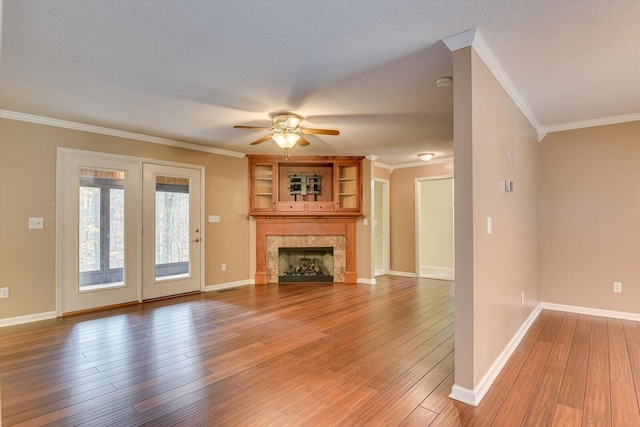 unfurnished living room with hardwood / wood-style floors, ceiling fan, ornamental molding, a textured ceiling, and a tiled fireplace