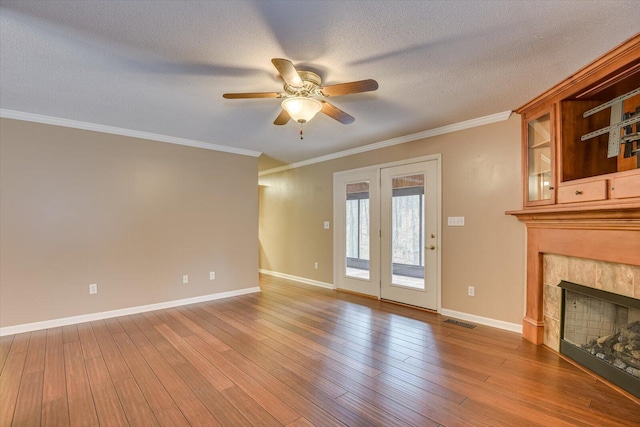 unfurnished living room featuring crown molding, ceiling fan, a textured ceiling, a fireplace, and wood-type flooring