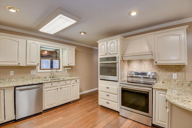 kitchen featuring appliances with stainless steel finishes, custom range hood, crown molding, and sink