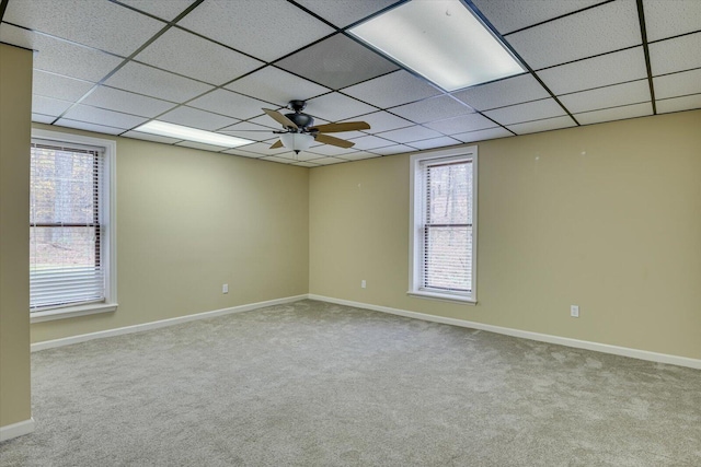 spare room with a paneled ceiling, light colored carpet, ceiling fan, and a healthy amount of sunlight