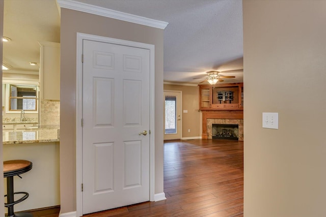 hallway with sink, dark wood-type flooring, a textured ceiling, and ornamental molding