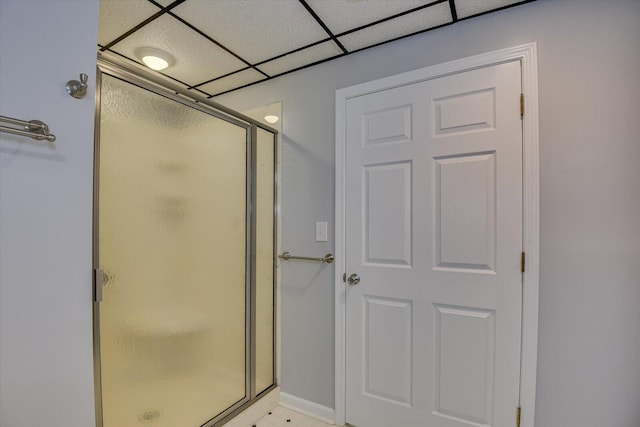 bathroom featuring a paneled ceiling and a shower with door