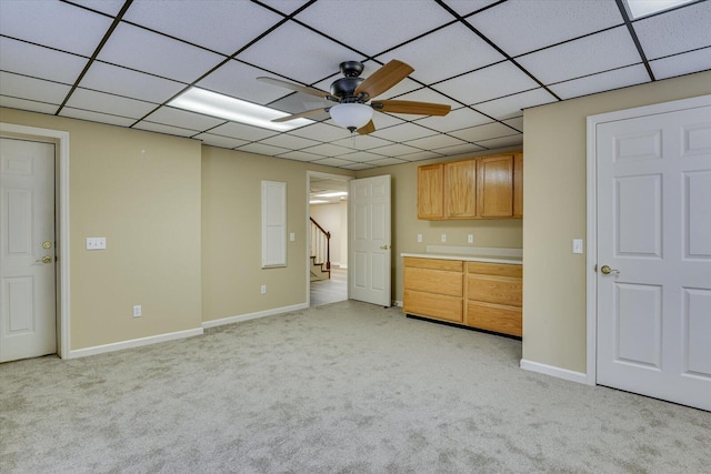 interior space featuring ceiling fan, a drop ceiling, and light colored carpet