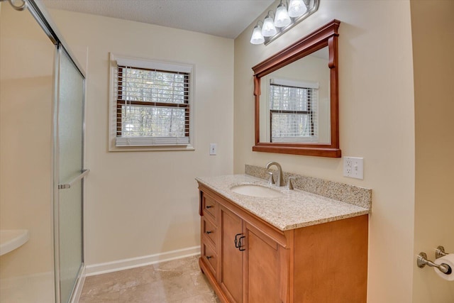 bathroom with vanity, a shower with shower door, and a wealth of natural light