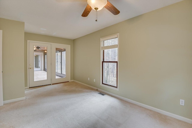 carpeted spare room featuring ceiling fan and plenty of natural light