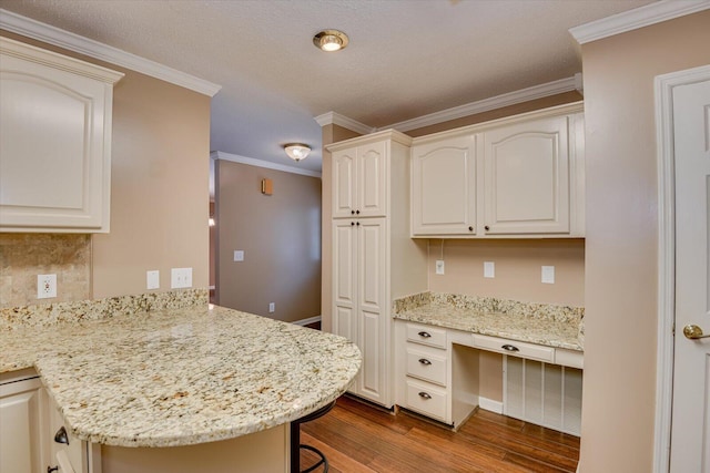 kitchen with a breakfast bar area, light stone countertops, and built in desk