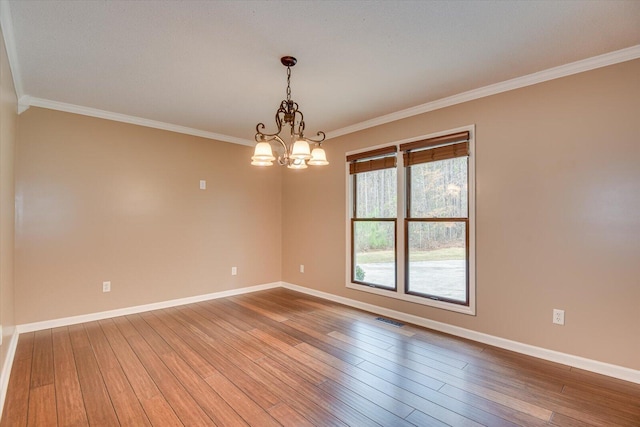 empty room with hardwood / wood-style flooring, a chandelier, and ornamental molding