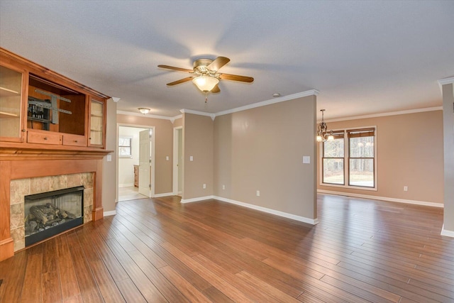 unfurnished living room featuring hardwood / wood-style floors, ceiling fan with notable chandelier, ornamental molding, and a tiled fireplace