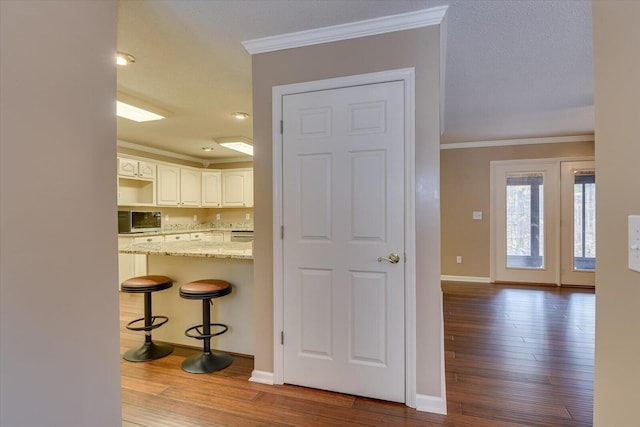 kitchen with white cabinets, a kitchen breakfast bar, light stone counters, and wood-type flooring