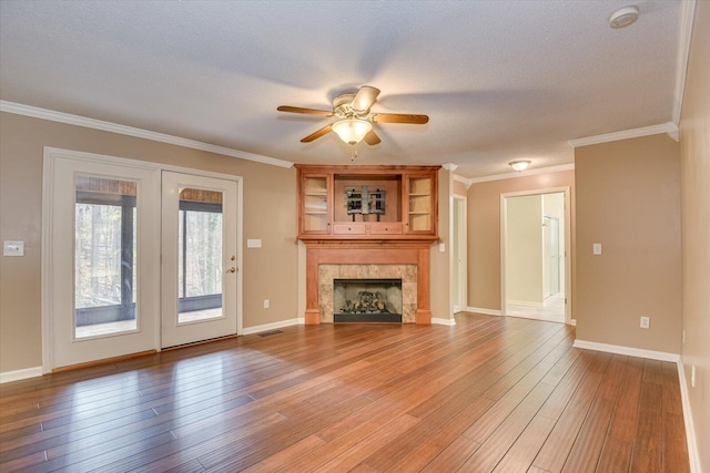 unfurnished living room with a tile fireplace, light hardwood / wood-style flooring, ceiling fan, and ornamental molding