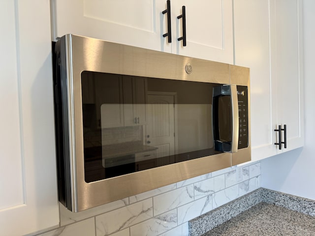 213 Whiskey Rd, Grovetown, GA 30813 - interior details with white cabinetry, light stone countertops, and stainless steel microwave