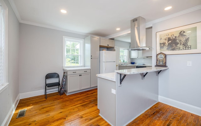 2217 Montclair St, Augusta, GA 30904 - kitchen featuring freestanding refrigerator, a kitchen bar, a peninsula, island range hood, and crown molding
