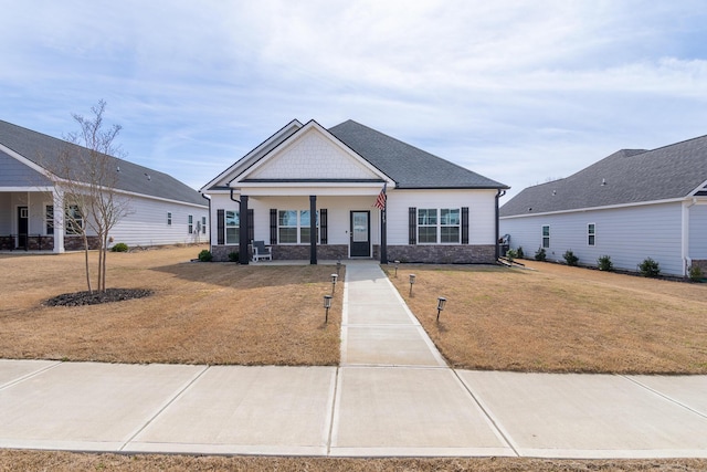 craftsman house with covered porch, roof with shingles, and a front yard