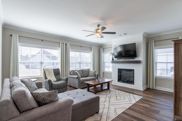 living room with a wealth of natural light, visible vents, crown molding, and wood finished floors